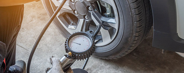 Close up mechanic inflating put air into the tyre and checking air pressure with gauge pressure in service station          