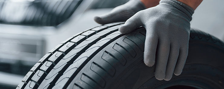 Hands only. Mechanic holding a tire at the repair garage. Replacement of winter and summer tires