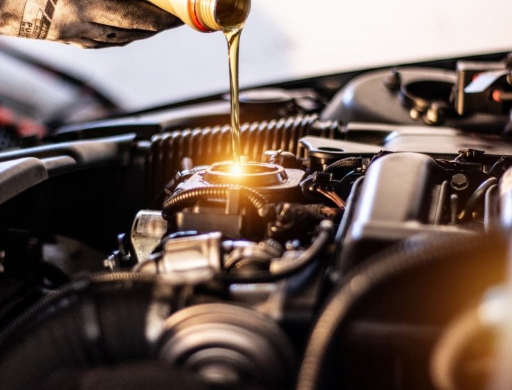 une personne qui verse de l'huile dans un moteur de voiture