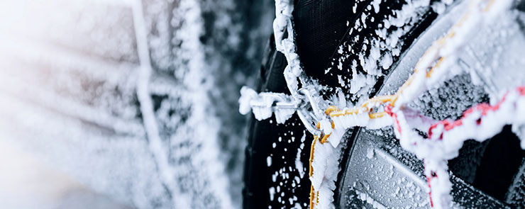 Car tire with snow chains on on snowy winter day