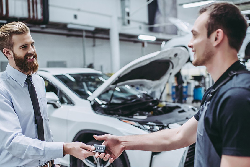deux hommes se serrant la main devant une voiture