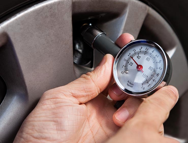 une personne vérifie une jauge de pression des pneus