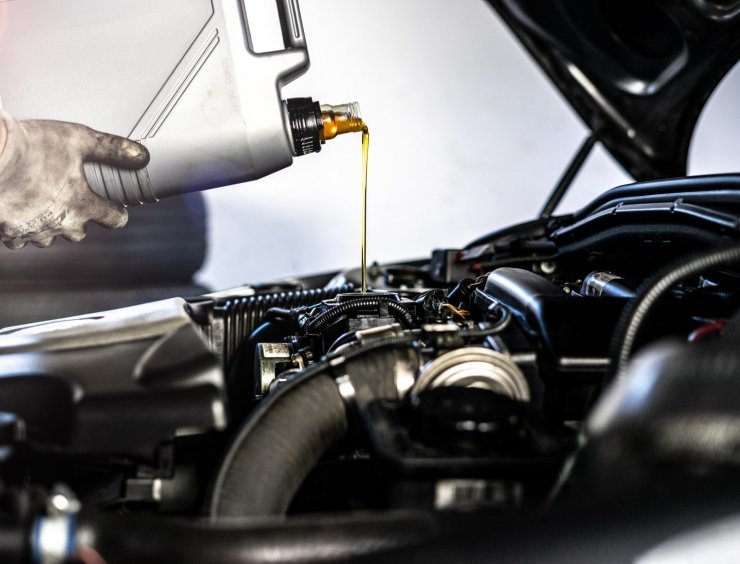 une personne qui verse de l'huile dans un moteur de voiture