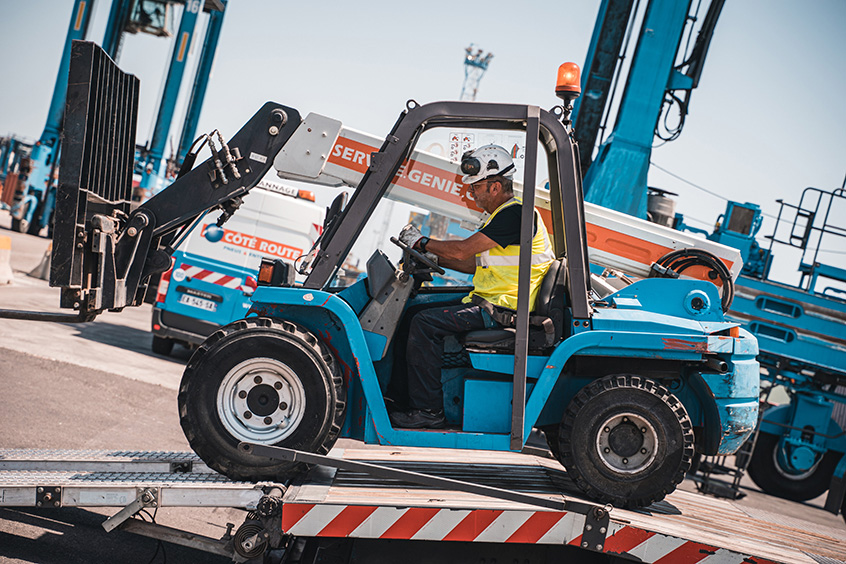 Un homme conduisant un chariot élévateur en haut d'une route
