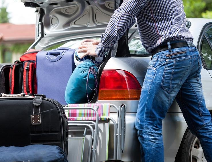 un homme qui met des bagages dans le coffre d'une voiture