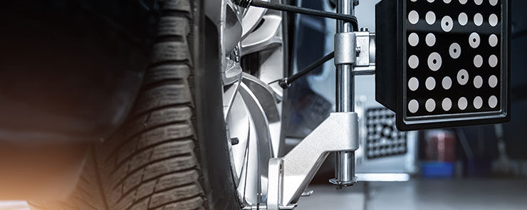 CLose-up car wheel indoors service maintenance repair center against laser sensor equipment diagnostics and 3d wheel alignment. Vehicle inside garage workshop for auto camber toe check fixing work